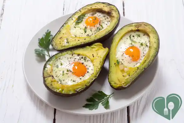 Baked eggs in halved avocados, sprinkled with herbs and black pepper — a fast, low-carb diabetic breakfast option.