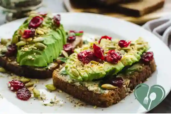 Two slices of whole grain toast topped with avocado, seeds, and unsweetened dried cranberries – vegan diabetic breakfast