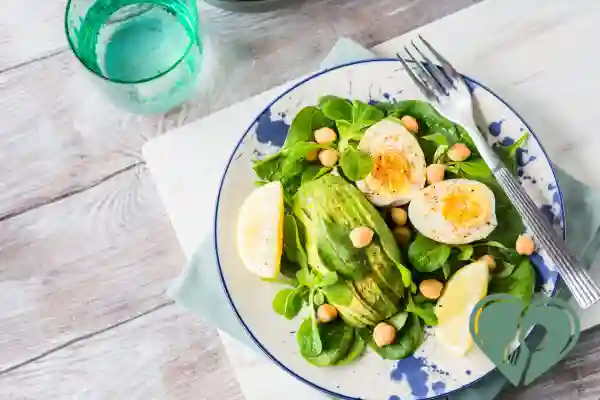 Boiled eggs, avocado, chickpeas, and spinach on a salad plate — a balanced low-carb, high-protein meal for blood sugar control