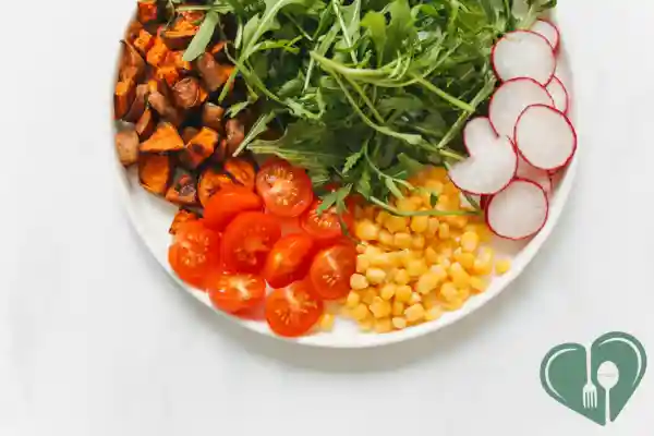 Colorful plant-based diabetic meal with sweet potatoes, arugula, radishes, tomatoes, and corn