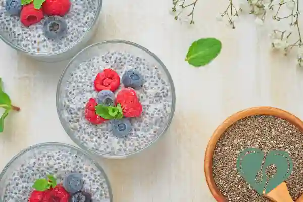Vegan chia pudding in glass jars topped with raspberries, blueberries, and mint – diabetic-friendly breakfast