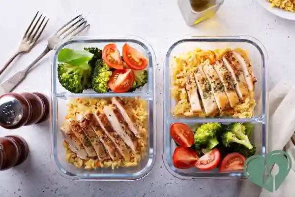 Two glass containers with grilled chicken breast, steamed broccoli, cherry tomatoes, and rice — balanced diabetic-friendly freezer meals.