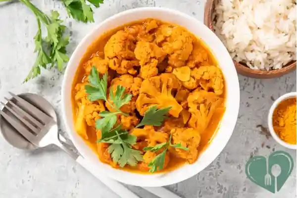 Cauliflower curry served in a bowl with a side of white rice