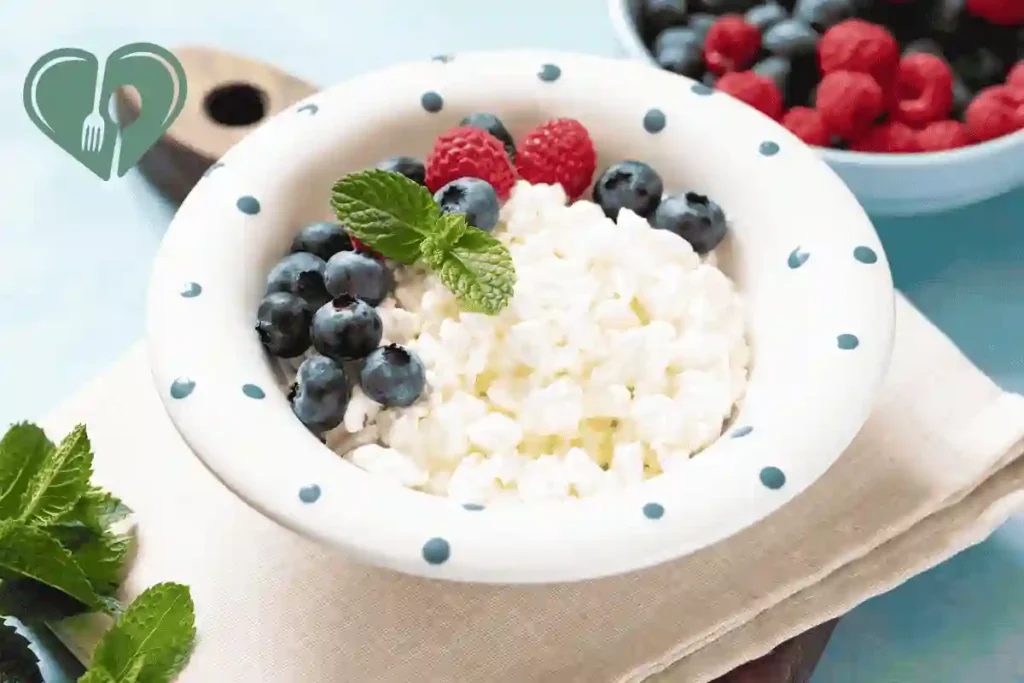 Cottage cheese served in a white bowl with blueberries, raspberries, and fresh mint leaves