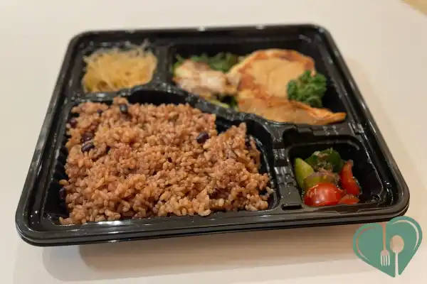 Bento lunch box with portioned sections of brown rice, grilled chicken, and vegetables for diabetic portion control.