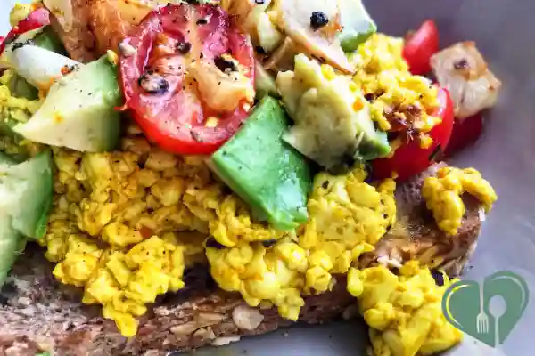 Tofu scramble on whole grain toast with avocado and tomatoes