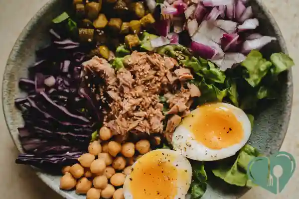A balanced diabetic-friendly dinner bowl with tuna, soft-boiled eggs, chickpeas, purple cabbage, and leafy greens