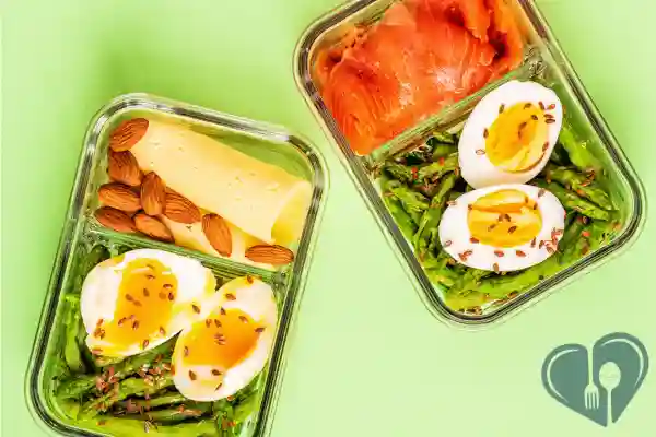 Low-carb snack boxes with soft-boiled eggs, smoked salmon, asparagus, cheese slices, and almonds – diabetic-friendly lunch prep.