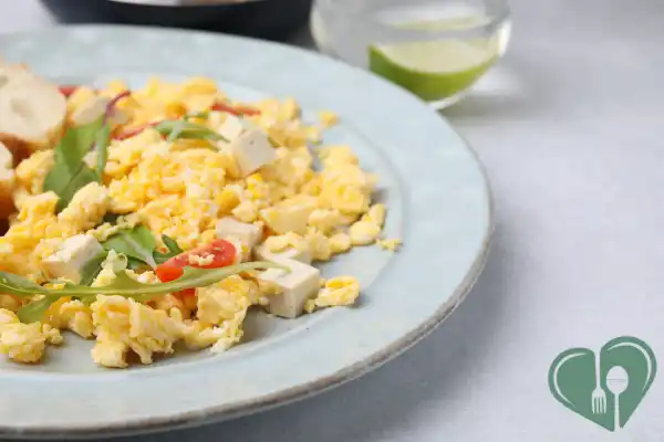 Plate of scrambled eggs with tofu cubes and fresh vegetables — a savory, diabetic-friendly breakfast option.