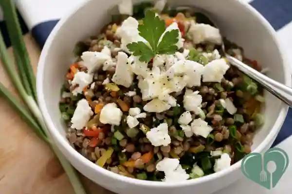 arm lentil salad with vegetables and feta cheese in a white bowl