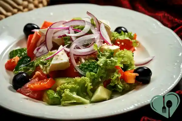 Mediterranean salad with feta, red onion, olives, and fresh vegetables on a white plate