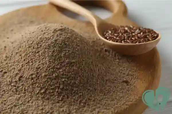 Ground flaxseed powder with whole flaxseeds in a wooden spoon