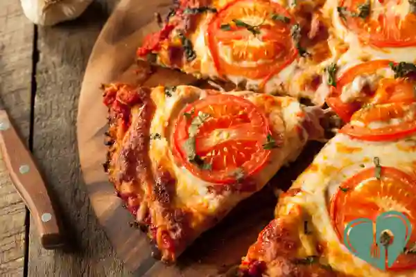 Sliced zero-carb pizza with tomato topping on wooden board, ready to serve