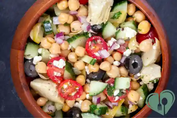 Mediterranean chickpea salad with cucumbers, cherry tomatoes, black olives, feta cheese, and artichokes – diabetic-friendly plant-based lunch.