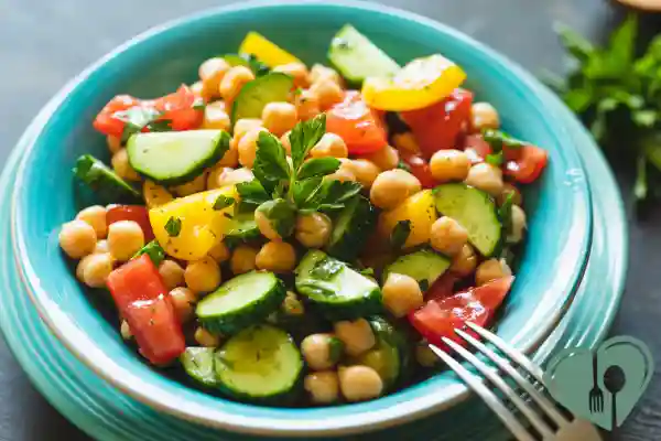 Colorful chickpea salad with cucumber, tomatoes, and herbs served in a turquoise bowl