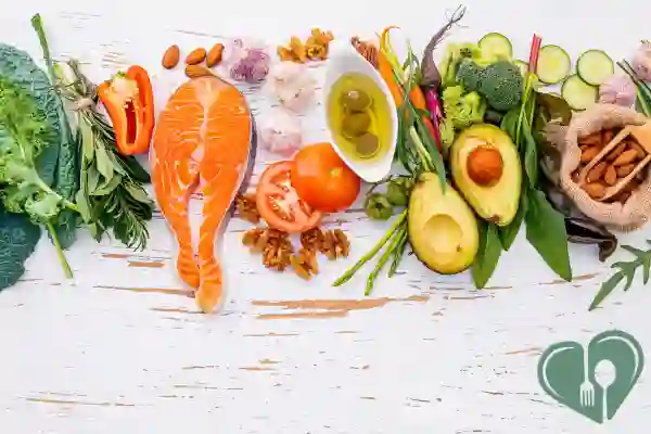 Flat lay of healthy cooking ingredients for diabetics including salmon, olive oil, avocado, fresh vegetables, nuts, and herbs