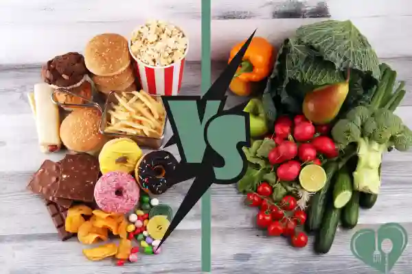 A visual comparison showing unhealthy processed foods like burgers, fries, chocolate, and donuts on the left, versus fresh vegetables like cabbage, cucumbers, peppers, and tomatoes on the right, with a bold "VS" graphic in the center.