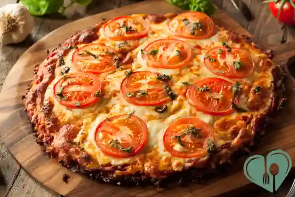 Baked zero-carb pizza crust topped with fresh tomatoes and herbs on a wooden board