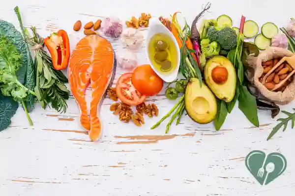 A flat lay of healthy low-carb foods including salmon, avocado, olive oil, nuts, and fresh vegetables — ideal for a savory diabetic breakfast.