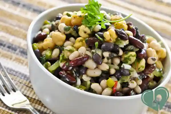 Mixed bean salad with parsley, chickpeas, kidney beans, and black beans in a white bowl