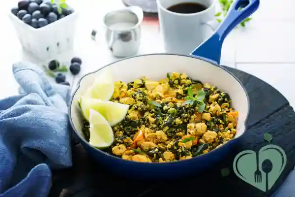Tofu scramble with vegetables and greens in a skillet, served with lime wedges — a low-carb, diabetic-friendly breakfast.