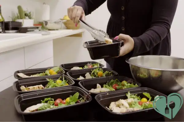 Preparing diabetic-friendly meal prep lunches with chicken, fresh greens, and cherry tomatoes in portion containers