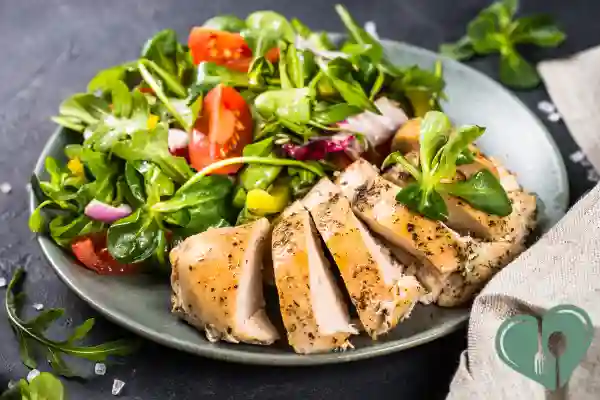 Plate of grilled chicken breast slices served with a fresh spinach and mixed greens salad with cherry tomatoes – a perfect diabetic-friendly lunch.