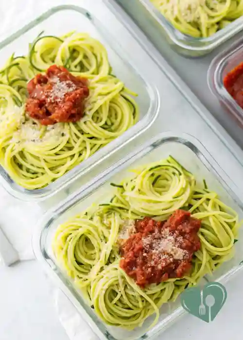 Zucchini noodles with turkey bolognese portioned in glass meal prep containers