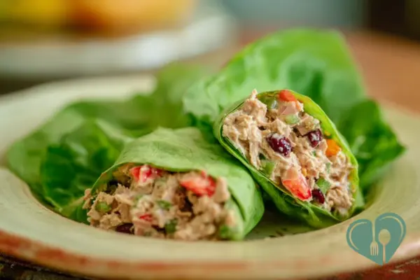 Close-up of tuna salad wraps cut in half with crunchy vegetables and herbs on a simple plate