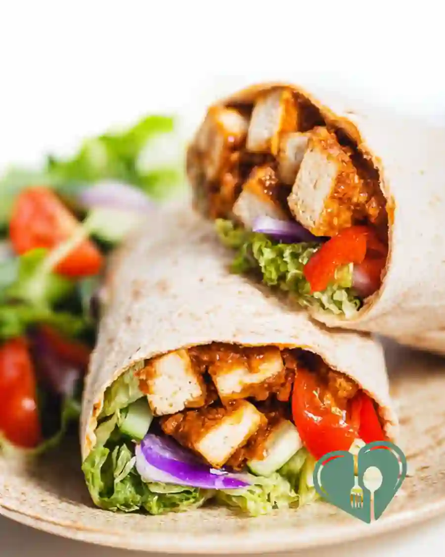 Crispy tofu wrap with fresh lettuce and red onion in a soft tortilla