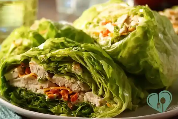 Close-up of turkey and cheddar lettuce wraps folded with fresh greens on a plain plate