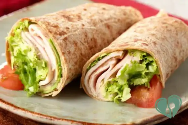 Turkey avocado wraps with fresh ingredients in a soft tortilla on a simple plate